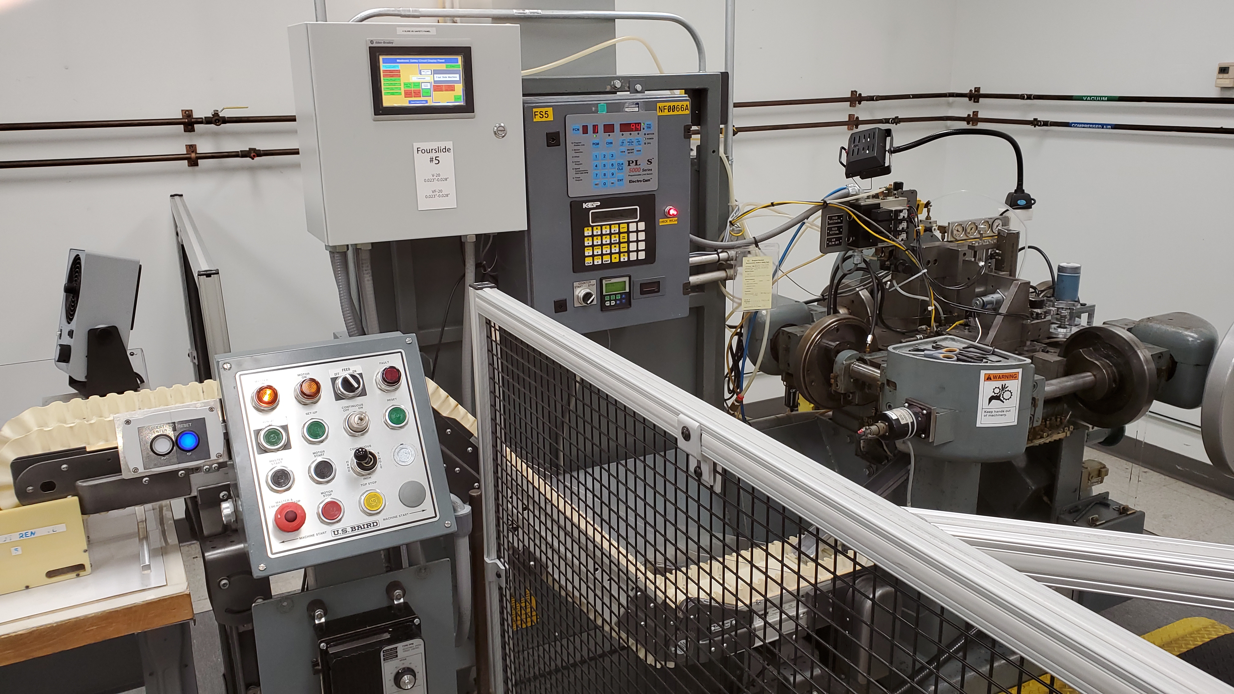 Production Four-Slide machine in operation inside guarded safety perimeter